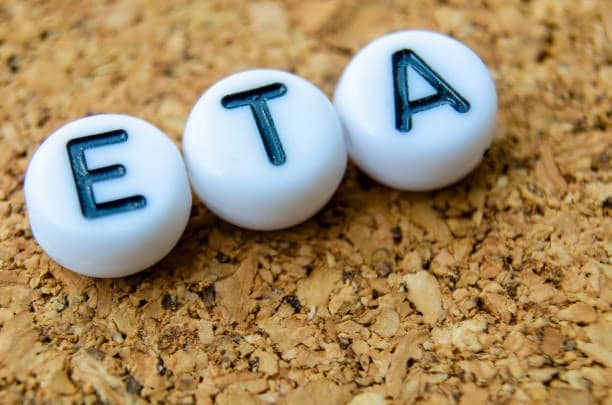 White beads with letters E, T, and A representing the concept of Estimated Time of Arrival, placed on a cork surface.