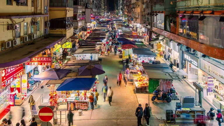 Elevated view of a bustling night market, illuminating the trade and commerce in an urban setting, highlighting the diverse aspects of local and international trade.