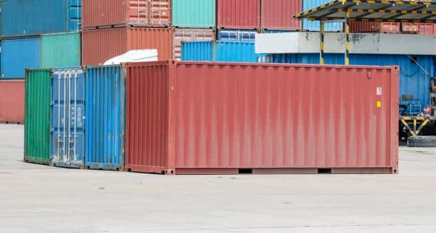 Multiple 20-foot shipping containers in a loading yard, ready for international export including shipments to India.
