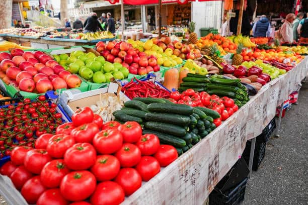 A vibrant display of fresh vegetables at a market stall, including tomatoes and cucumbers, showcasing goods typically involved in international import and export trade.