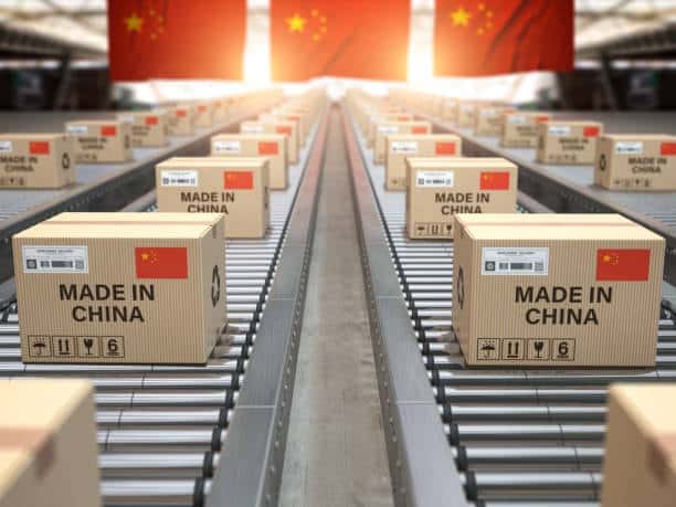 Numerous cardboard boxes labeled 'Made in China' on a conveyor belt, symbolizing mass production and export in global trade under a large Chinese flag.