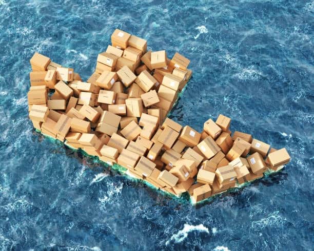 A mass of cardboard boxes forming the shape of a cargo ship floating in the ocean, symbolizing overloaded shipping systems and potential for demurrage penalties.