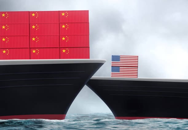 Two ships facing each other on the water, one with Chinese shipping containers and the other with a US flag, representing international trade.