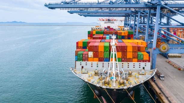 Large container ship docked at a Chinese port being loaded with cargo, representing the beginning of international shipping routes and affecting delivery times from China.