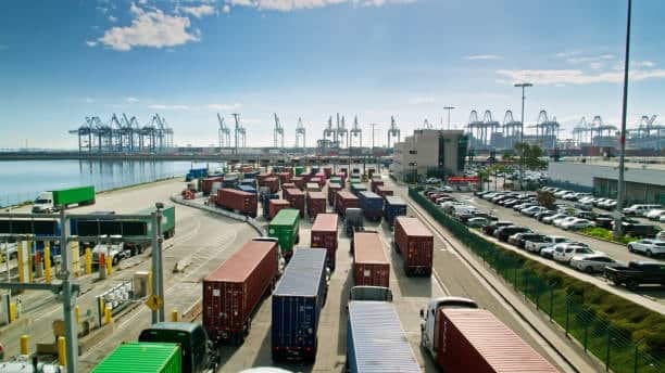 Container trucks lined up at a congested port terminal, highlighting the severe bottlenecks and delays in cargo movement due to port congestion.