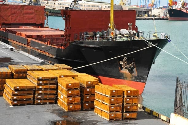 Stacked wooden crates of heavy cargo at a port awaiting sea freight shipping.