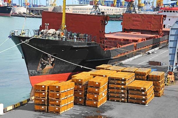 Heavy green crates positioned at port for low-cost bulk sea shipment.