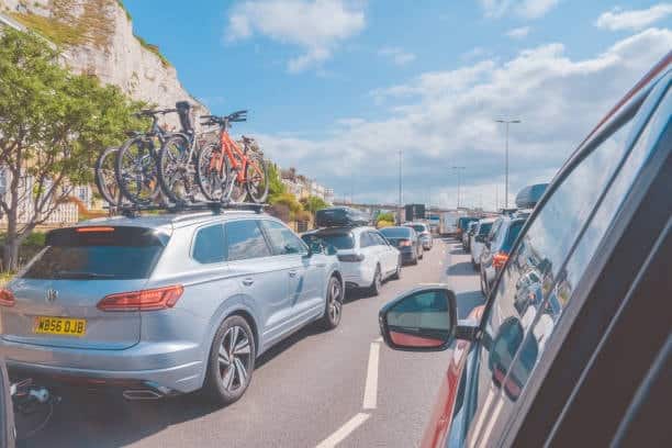 Line of cars stuck in heavy traffic near a port entry point, demonstrating how port delays affect not just cargo but also passenger vehicle flow and travel schedules.