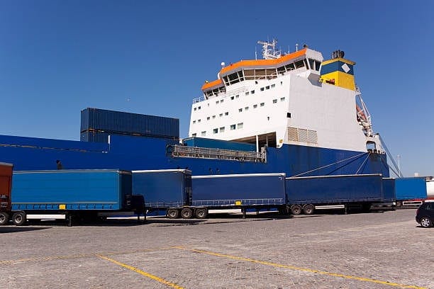 Roll-on/roll-off ferry at port being loaded with long trailers for heavy cargo shipping.