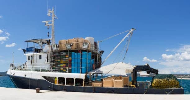 Small freight ship loaded with barrels and cargo for cost-efficient transport.
