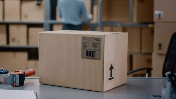 Cardboard box with label and up-arrow symbol prepared for Amazon FBA shipment in warehouse.