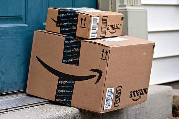 Amazon Prime boxes stacked at blue front door showing proper barcode and label placement.