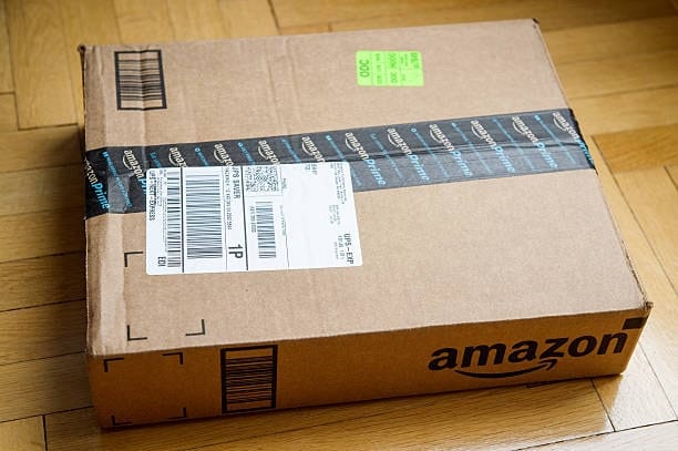 Amazon package with shipping label and barcode placed on wooden floor ready for dispatch.