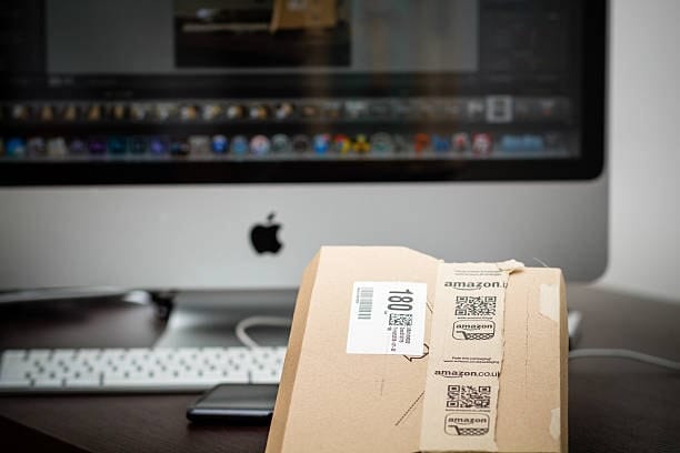 Amazon UK small package with QR-style shipping label placed near a desktop computer.