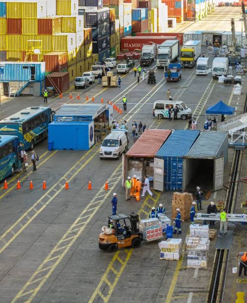 Busy customs clearance yard with open containers and logistics staff handling inspections.