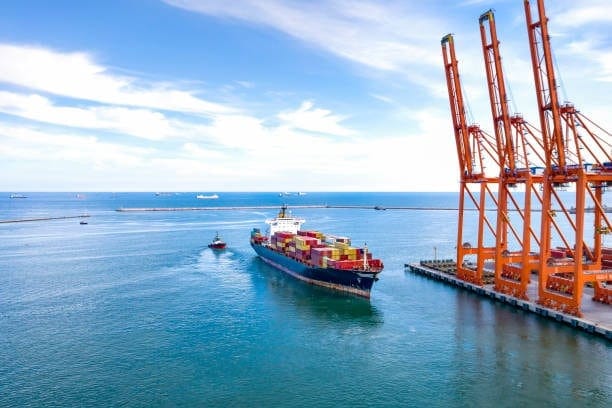 Cargo ship carrying shipping containers arriving at port as part of sea freight route from China to the USA.