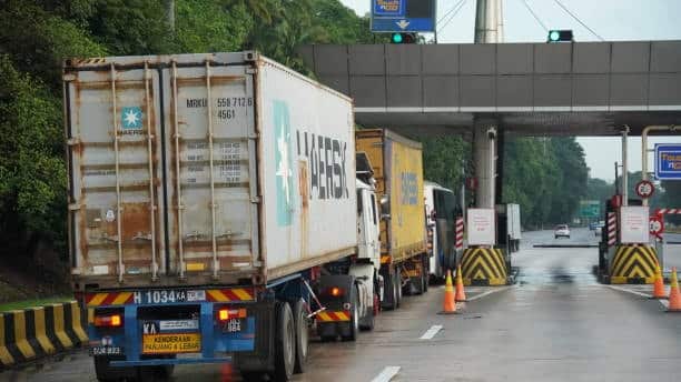 Cargo container trucks waiting in line for customs inspection at a border checkpoint.