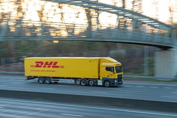 DHL freight truck driving on highway symbolizing the logistics support for shipments from China to the USA.