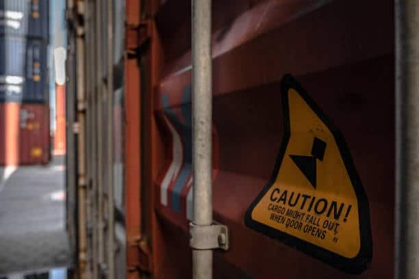 Close-up of caution label on freight container warning about cargo shift during unloading.