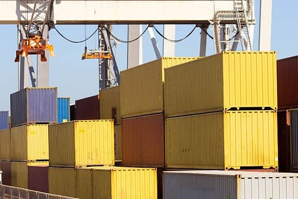 Shipping containers being handled by crane, representing freight out operations at port.