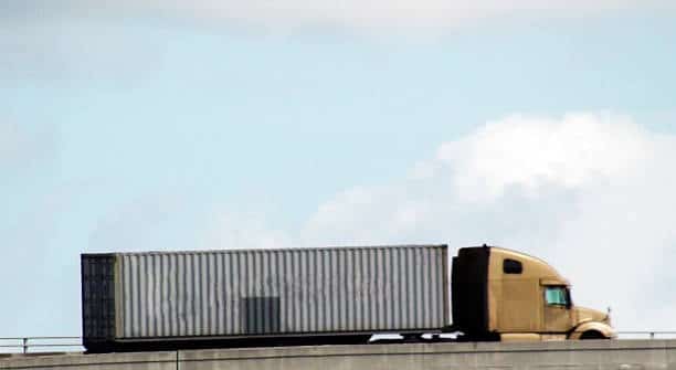 Semi-truck transporting a shipping container for outbound freight delivery.