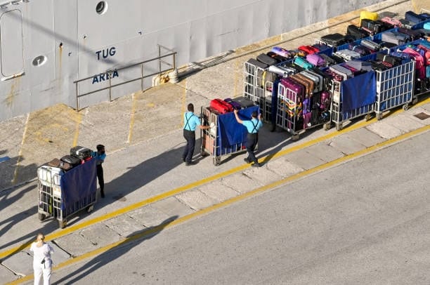 Customs officers handling luggage for inspection at a seaport terminal.