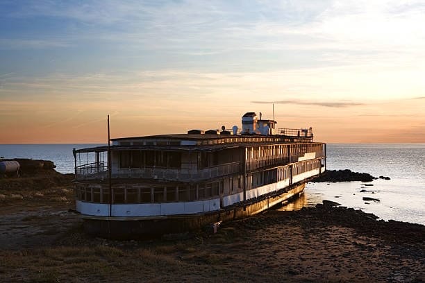 Abandoned passenger ship on the shore, illustrating outdated or non-operational shipping routes.