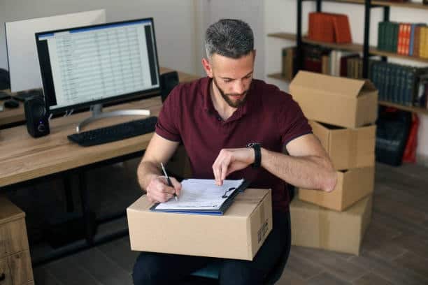 Logistics worker checking time while organizing package shipments from Canada to the United States.