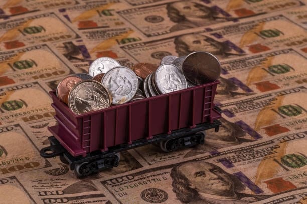 Train wagon filled with coins on dollar background showing freight value allocation under CPT shipping.