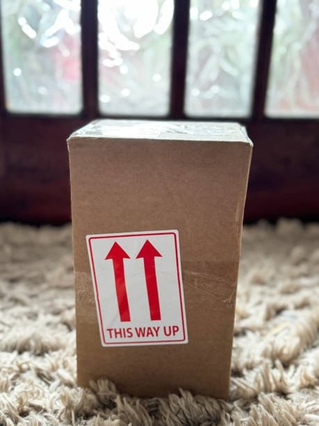 Cardboard box standing upright with 'This Way Up' label to indicate correct handling orientation.