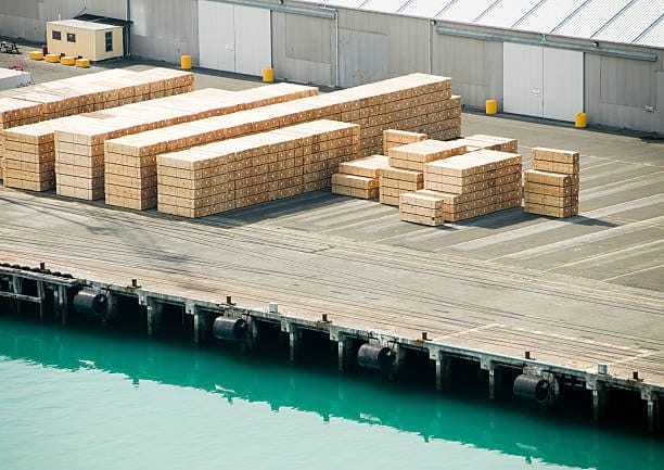 Timber products stacked for export at a shipping port in New Zealand.