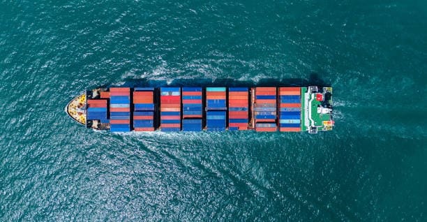 Top-down view of a fully loaded container ship on its sea freight route from China to the USA.