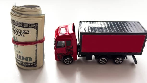 Red truck next to rolled U.S. dollars representing freight charges under CPT Incoterm.