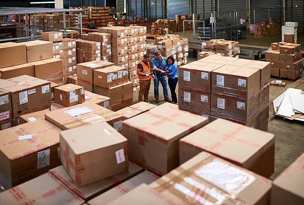 Warehouse workers managing and organizing oversized box shipments for logistics.