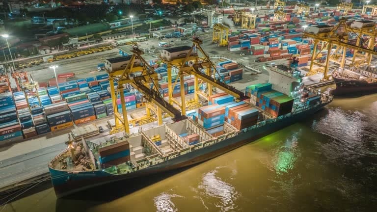 Nighttime port operations showing container loading for international shipments