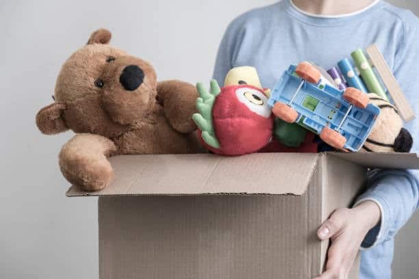 Person carrying a box of toys for import shipping preparation.